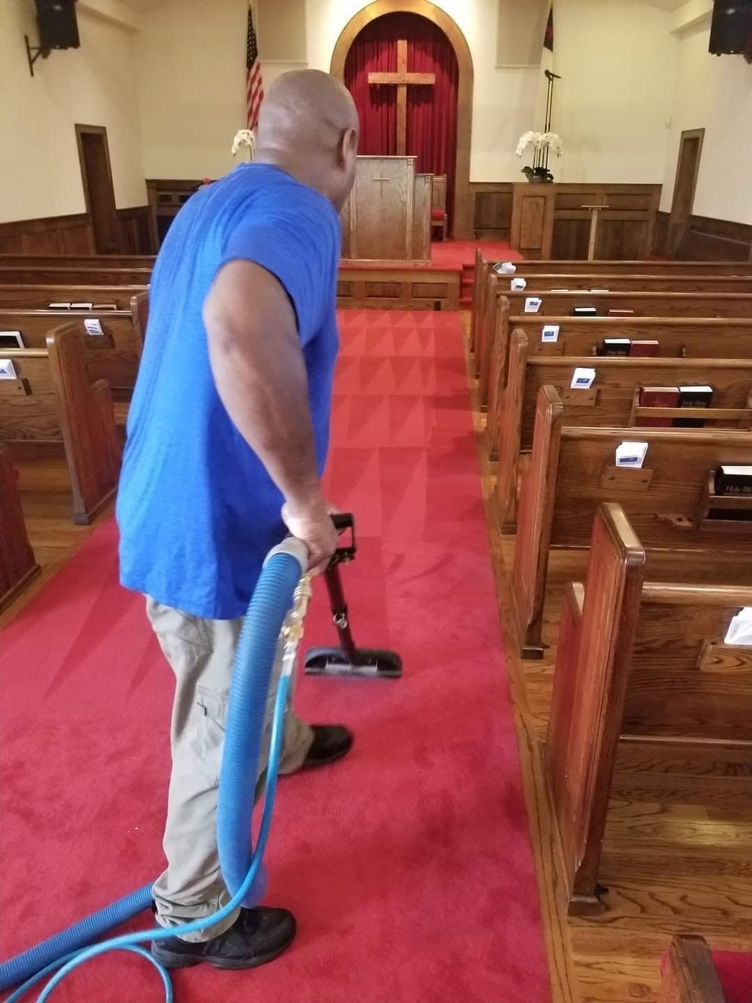 Technician cleaning red church carpet between pews
