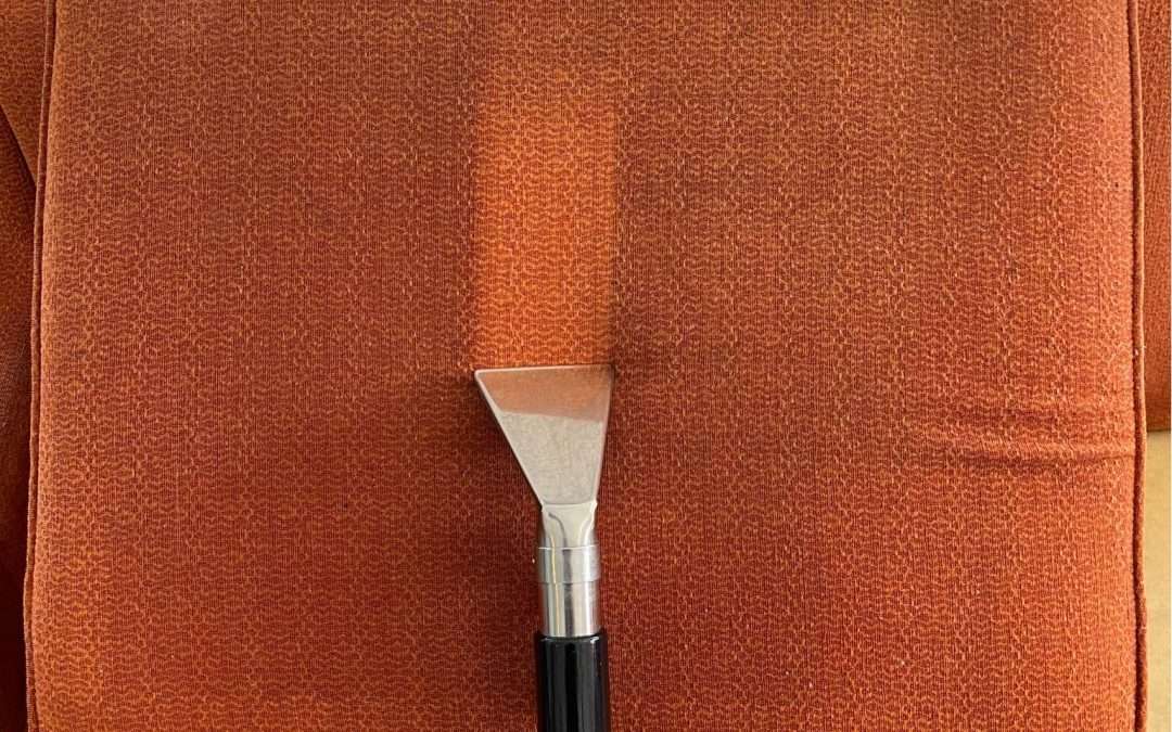 Upholstery cleaning tool on orange couch.